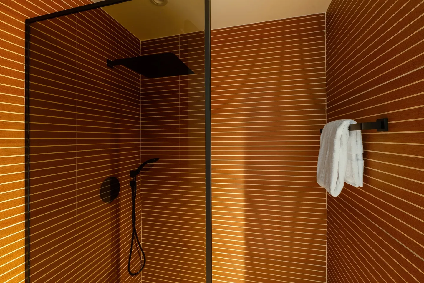 A bathroom with wooden panels and a glass shower enclosure.