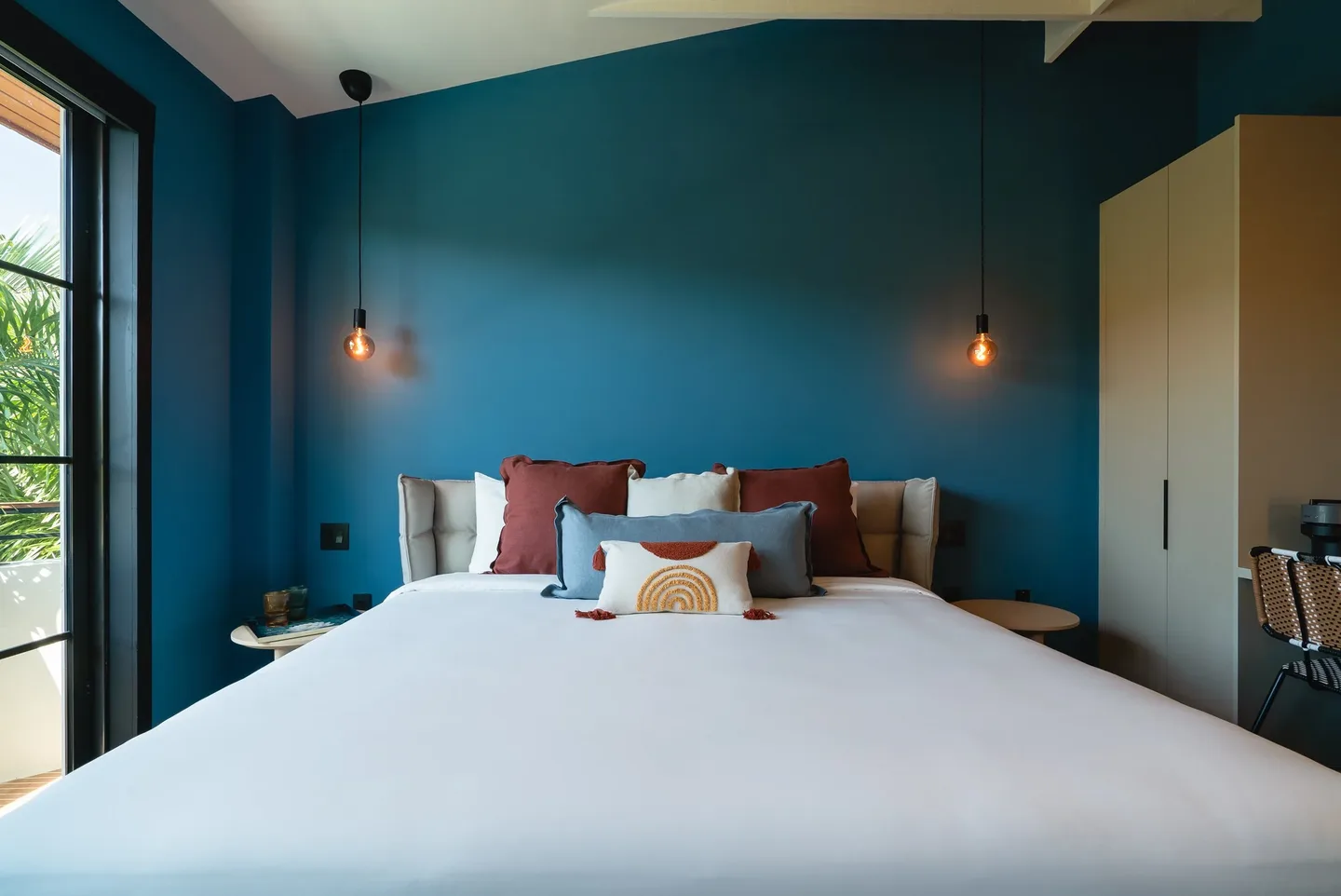 Bedroom with blue walls, white bed, and decorative pillows.