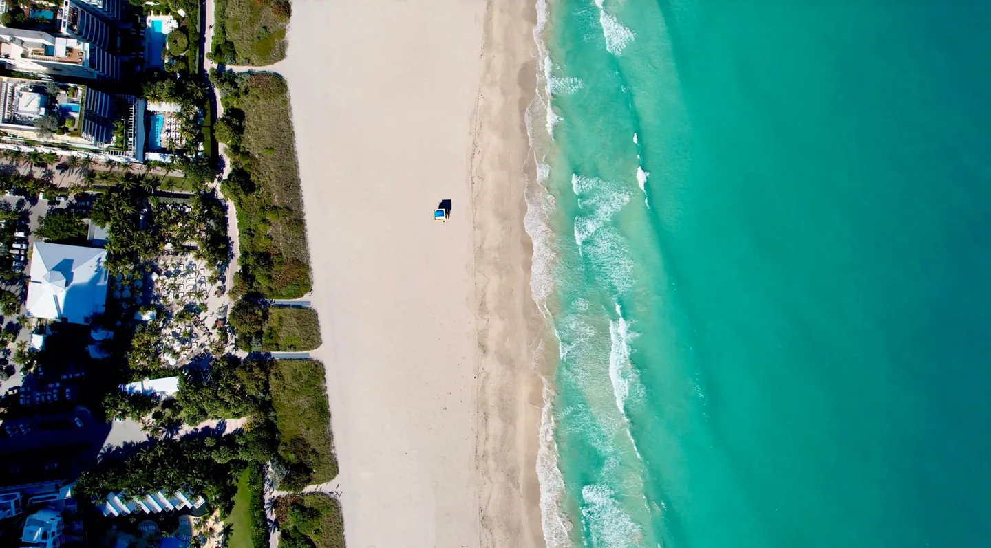 Aerial view of Miami Beach's coastline with turquoise water and sandy shoreline.